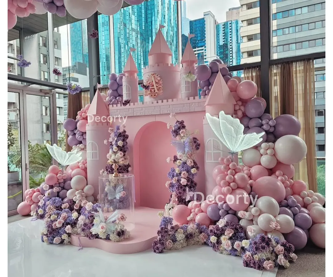 A fairytale comes to life with this stunning pink princess castle backdrop. Surrounded by a sea of pink and purple balloons and glowing butterflies, it's the perfect stage for a royal celebration.