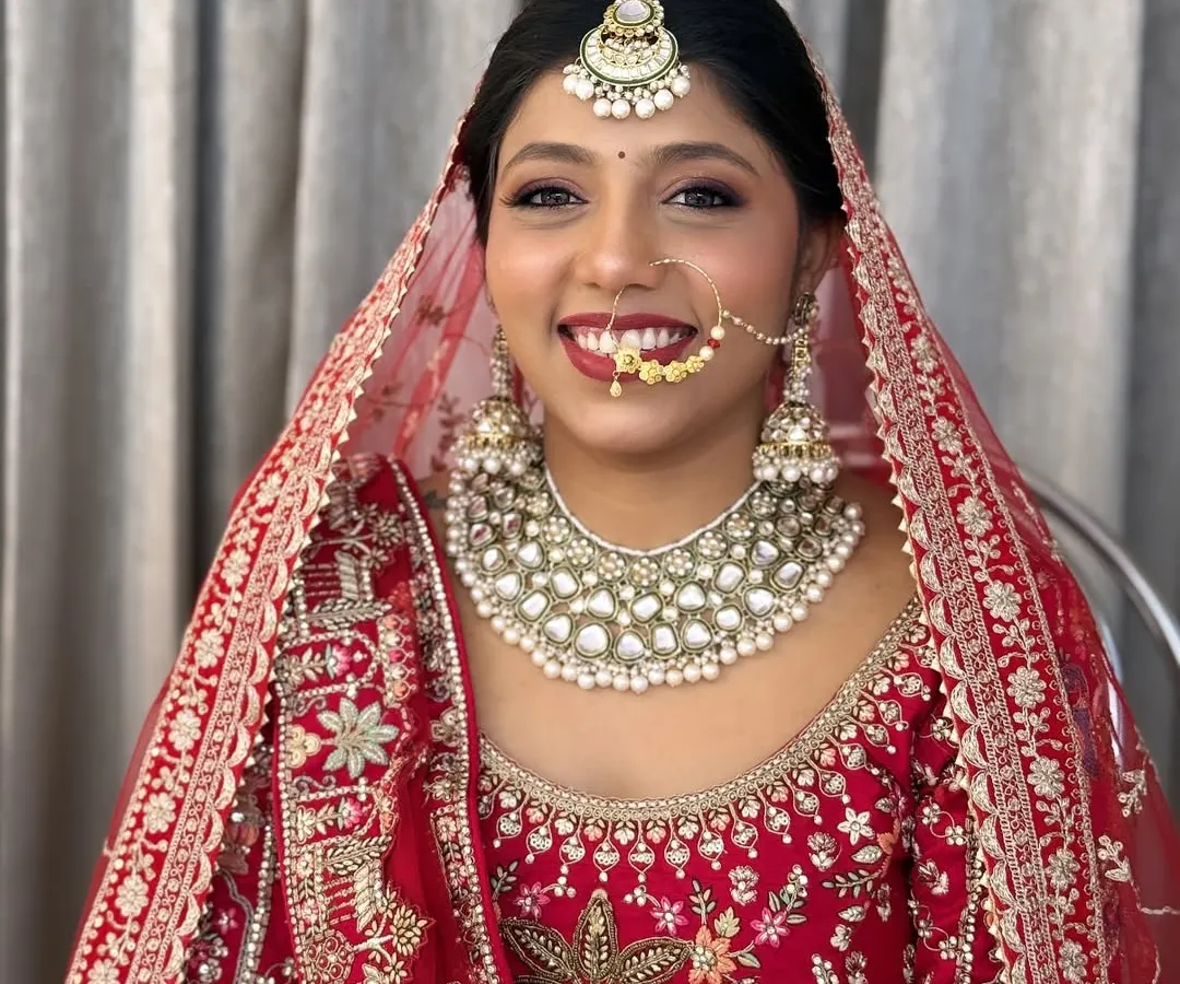 A radiant smile on a classic North Indian bride. I created this look with soft, glowing skin and a bold red lip to perfectly complement her stunning red lehenga for the main wedding ceremony.