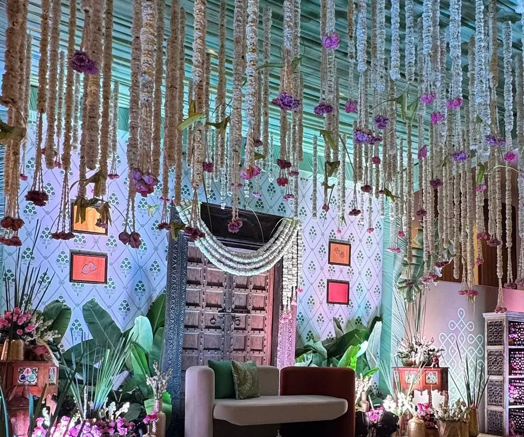 We designed this 'Southern Grace' baby shower entrance as a doorway to new life. The antique wooden door, traditional floral hangings, and lush greenery create a warm, inviting atmosphere rooted in cultural elegance.