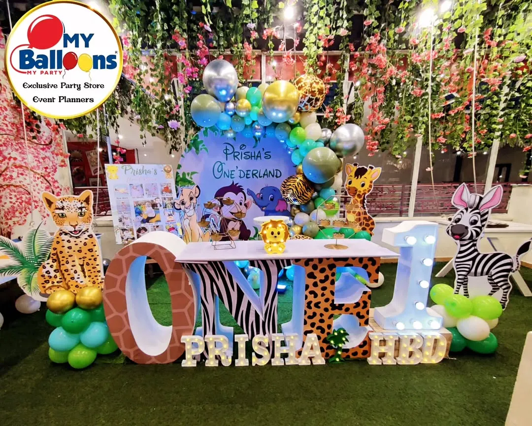 We transformed this space into a lush jungle for Prisha's "Onederland" party. The setup includes a large 'ONE' table with animal-print lettering, character cutouts of a leopard and zebra, and a backdrop of hanging foliage, creating a truly immersive wild animal adventure.