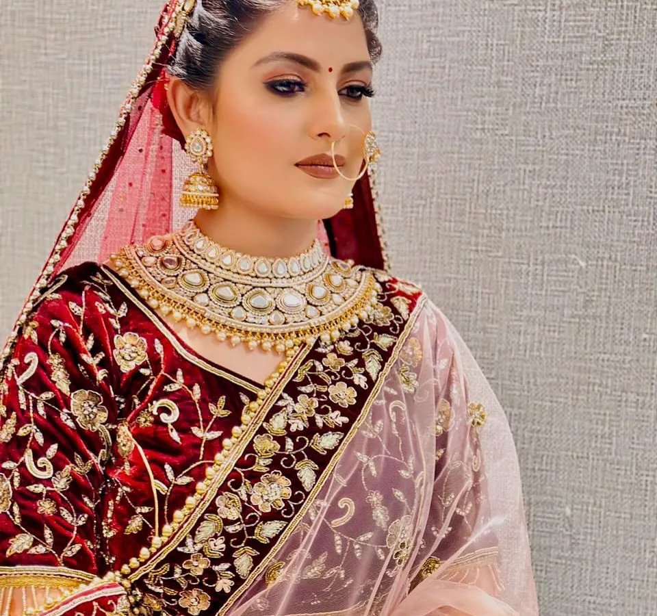 A picture of bridal perfection. This look features intricate hair styling with a traditional maang tikka and flawless HD makeup, highlighting the bride's natural beauty for her special day.