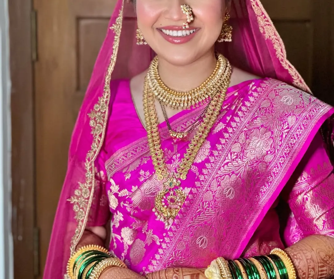 A modern Maharashtrian bride in all her glory. I loved creating this look, balancing the vibrant pink Banarasi silk with radiant skin and traditional gold jewelry for a timeless yet fresh feel.