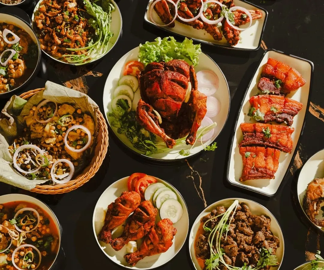 This is what a true Manipuri feast looks like. A table full of our specialties, including whole fried chicken, pork ribs, flavorful curries, and fresh salads, perfect for your large gatherings and parties.
