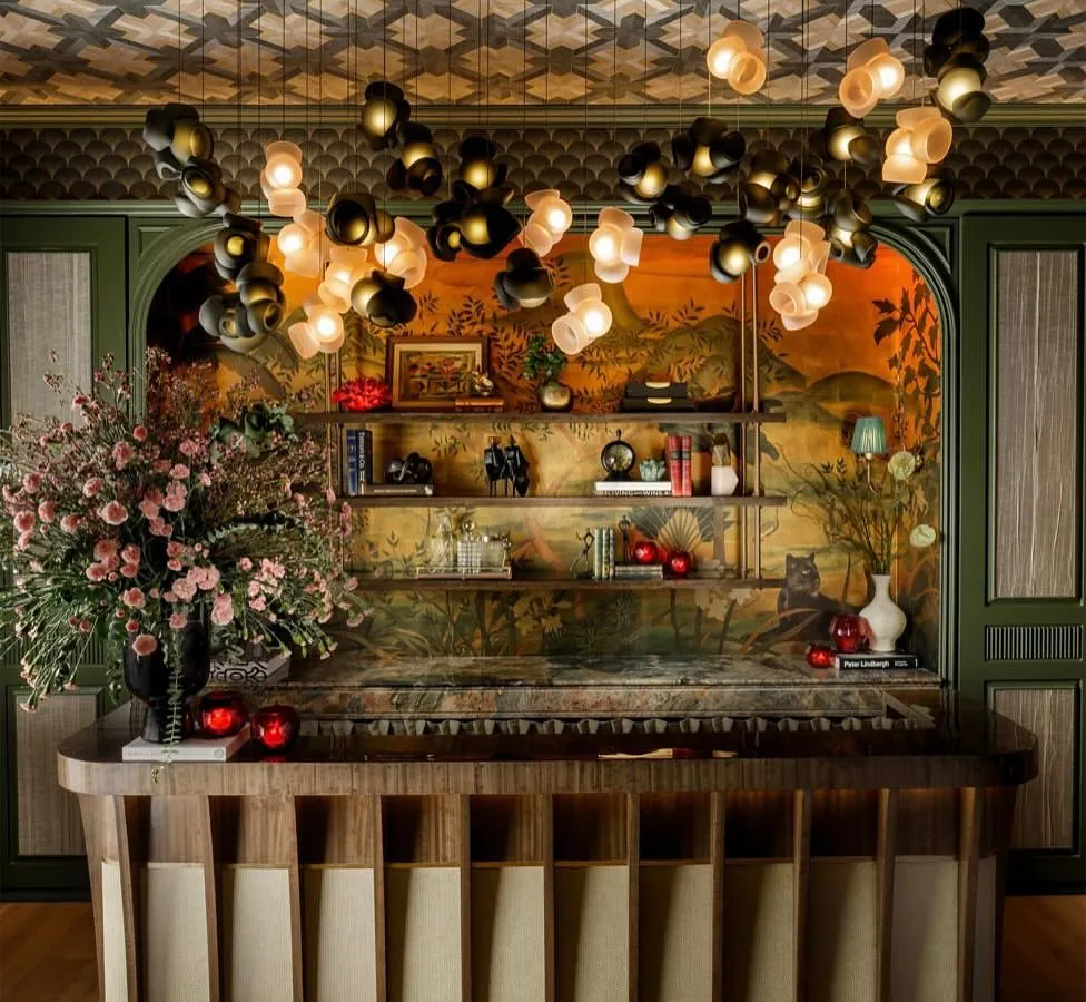 A custom installation of the Bocci 100 series flows over a bar, creating an immersive canopy of light. The interplay of dark and light pink glass forms provides a warm, ambient glow, demonstrating how I use clustered pendants to craft a unique atmosphere for commercial and hospitality environments.