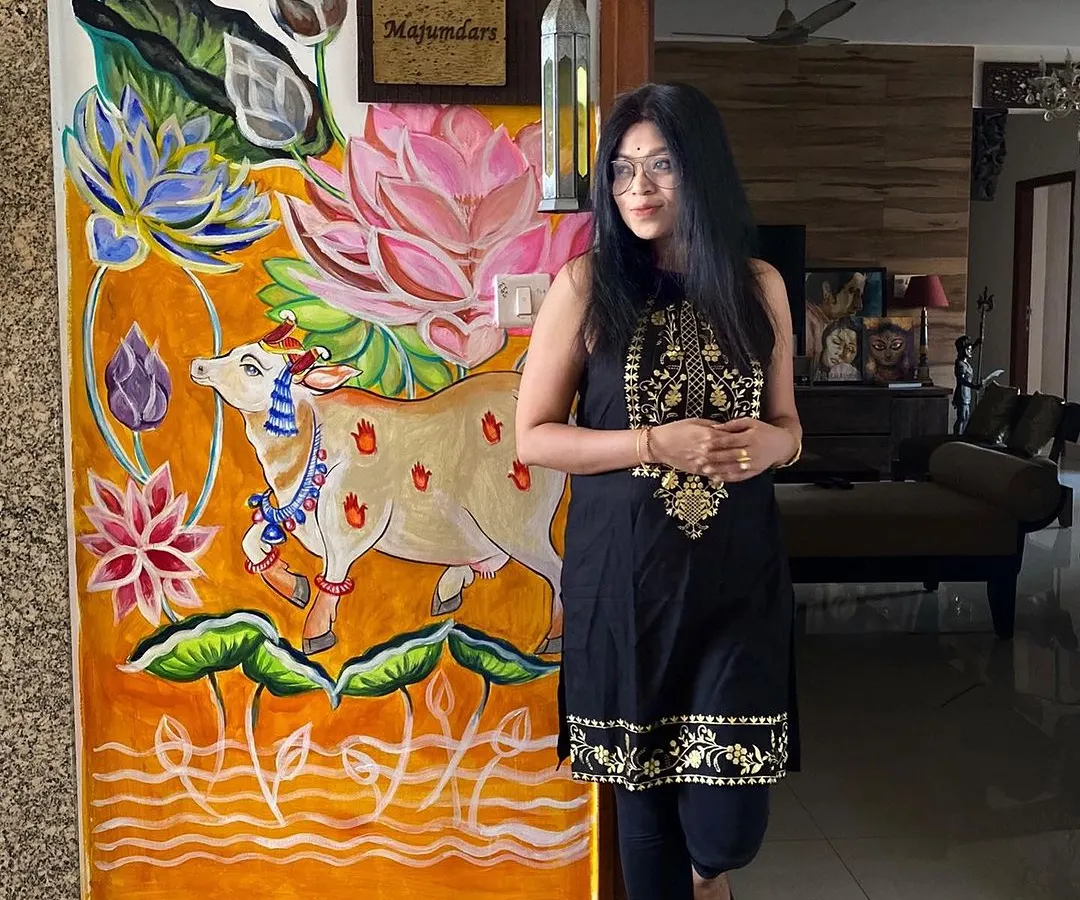 Here I am with a custom Pichwai-style mural I painted right at the entrance of my home. This piece, featuring a decorated cow and vibrant lotuses, shows how I adapt traditional Indian art to create a warm and personal welcome.