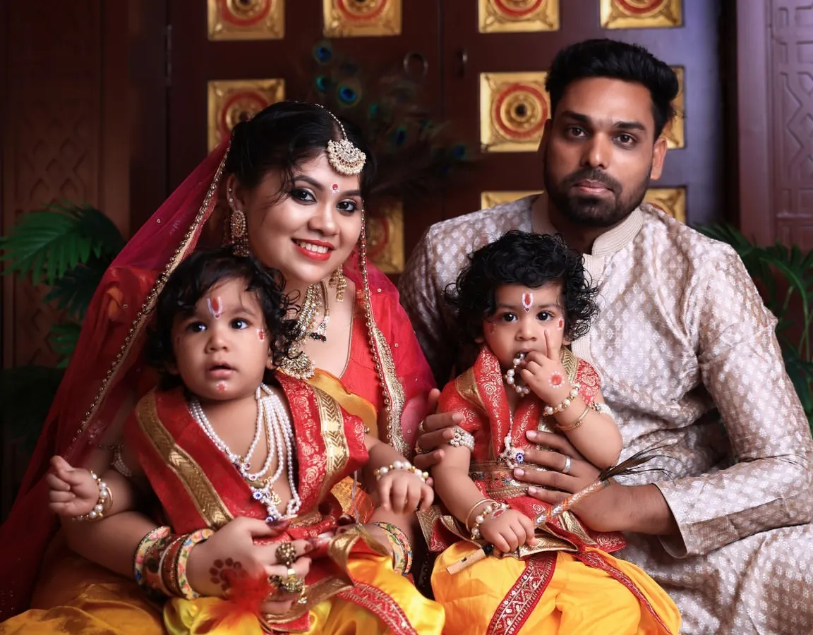 A complete family portrait celebrating Janmashtami. The parents are seated with their two young children, who are delightfully dressed as little Krishnas, showcasing our ability to create beautiful themed shoots for the whole family.