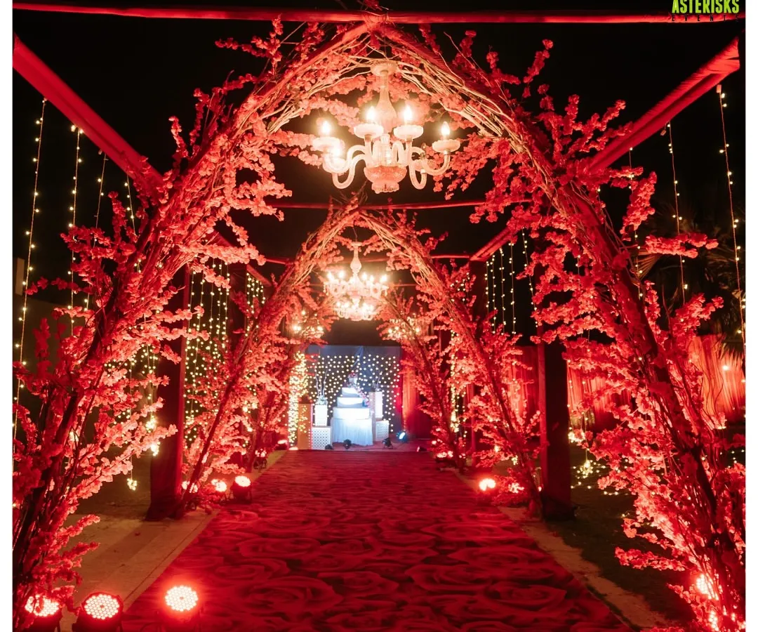 A breathtaking entrance for a night to remember. We designed this stunning red floral tunnel, complete with elegant chandeliers, to create a grand and romantic welcome for a reception at Sula Vineyards.