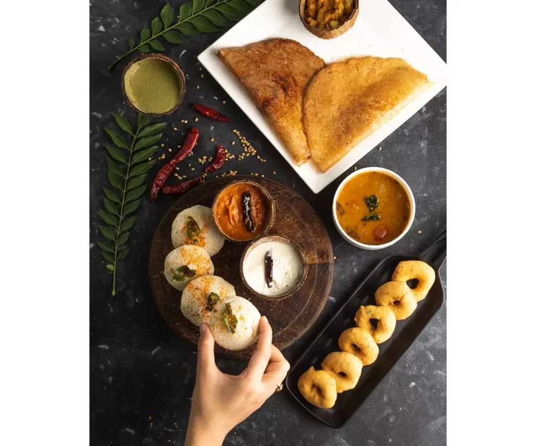 A complete South Indian breakfast spread, styled and shot for Double Tree by Hilton. This top-down flatlay captures the variety of the meal, from crispy dosas to savory sambar, perfect for a hotel menu.