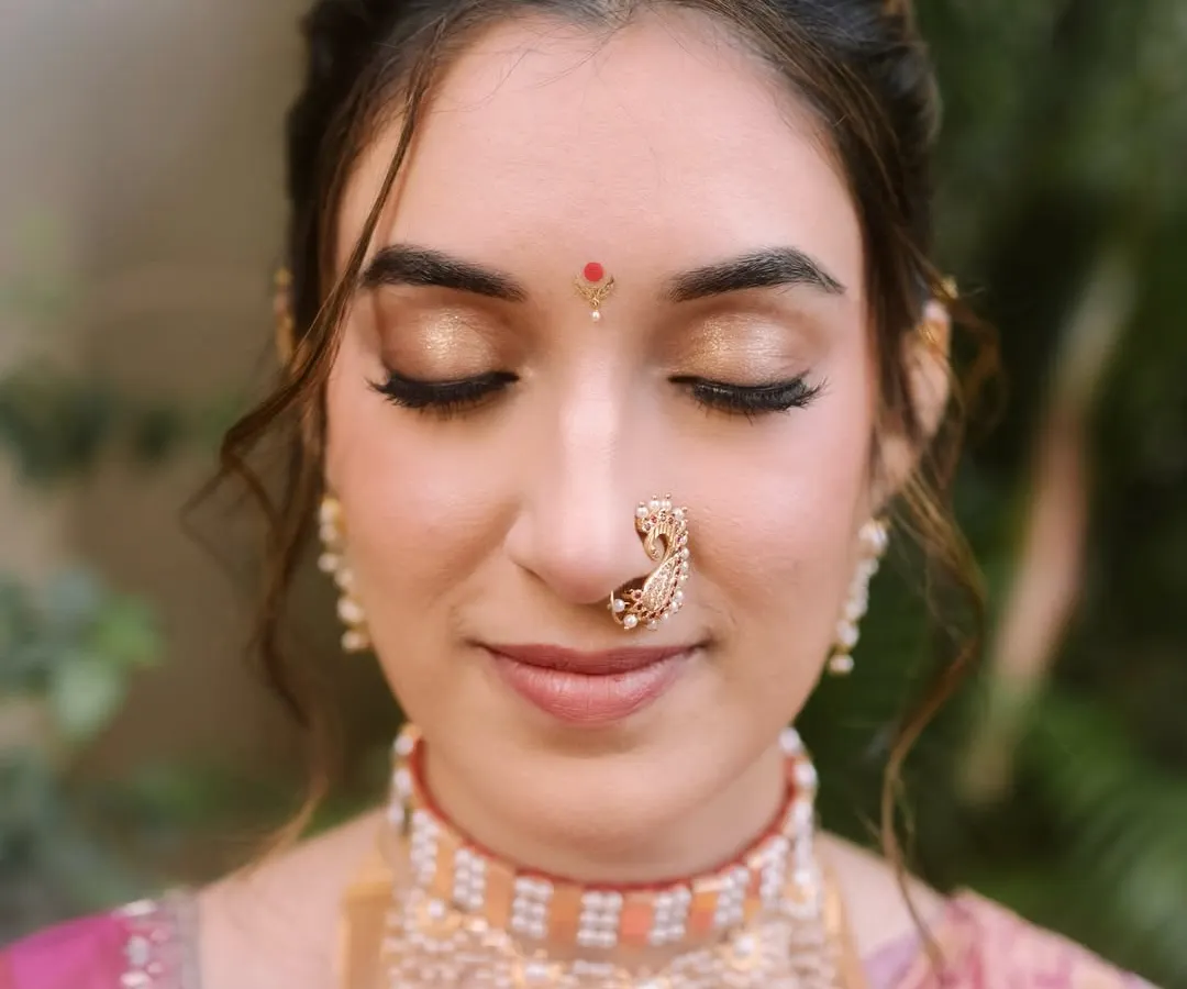 A close-up of Shalmali's classic bridal makeup. I focused on creating a neutral gold eyeshadow that beautifully complemented the zari of her Paithani saree and her skin tone. This is my signature minimal approach, ensuring every detail is balanced and graceful, especially in natural daylight.