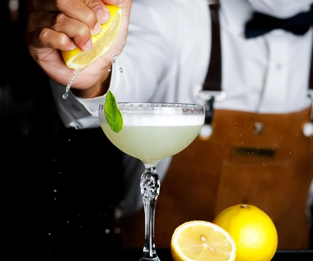 A great cocktail is an experience, and the photo should be too. Here, I captured the exact moment a fresh lemon is squeezed into a gin basil smash, highlighting the craft and freshness that goes into every drink.