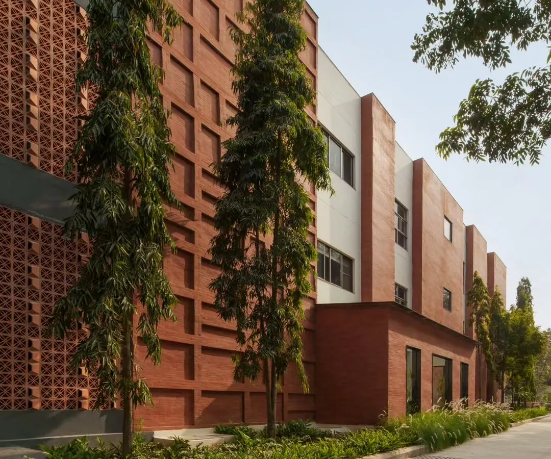 The facade of the Campus Biovet office block showcases our philosophy of using honest, regional materials. A double-walled brick cladding, inspired by the local brick factories of Malur, creates a textured, linear pattern that is softened by the surrounding landscape and tall trees we carefully preserved during construction.