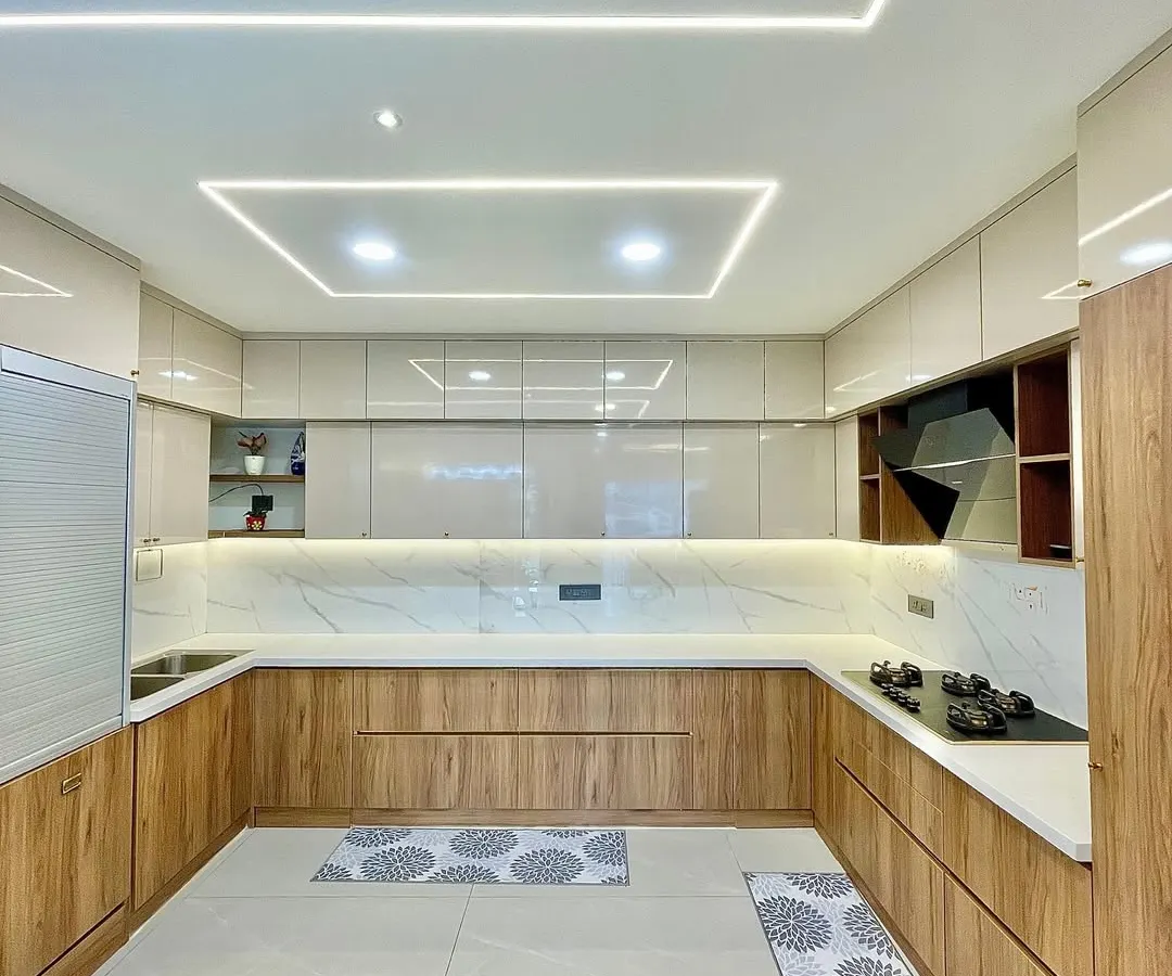 A modern U-shaped modular kitchen designed for ultimate functionality. Notice the seamless blend of wood-tone and high-gloss cabinets, complemented by integrated profile lighting for a bright and efficient cooking space.