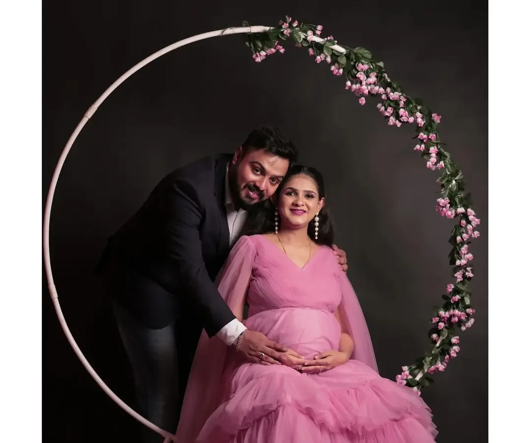 A beautiful moment from a maternity couple shoot. This shot features our popular pink tiered maternity gown and the floral ring prop, set against a classic dark backdrop to create a timeless portrait.