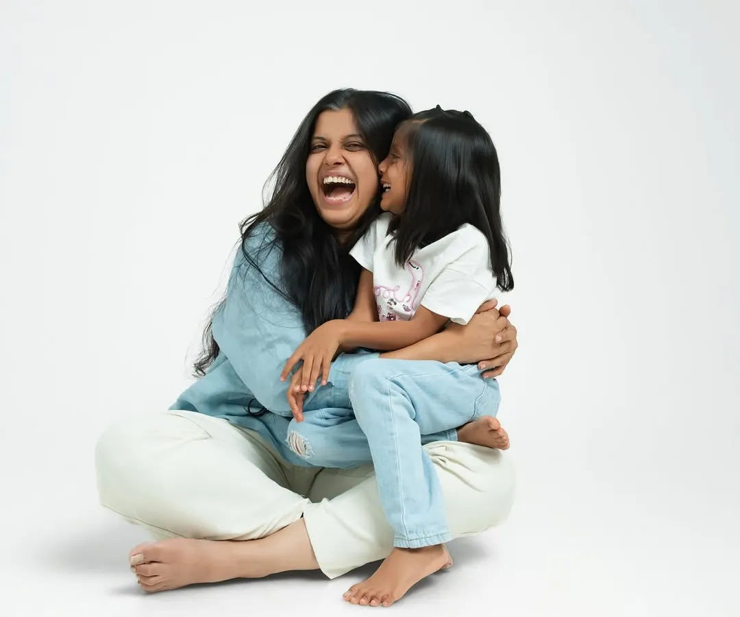 A mother and daughter sharing a moment of pure, uninhibited laughter in the studio. My clean, white backdrop ensures that nothing distracts from the genuine connection and happiness between them.