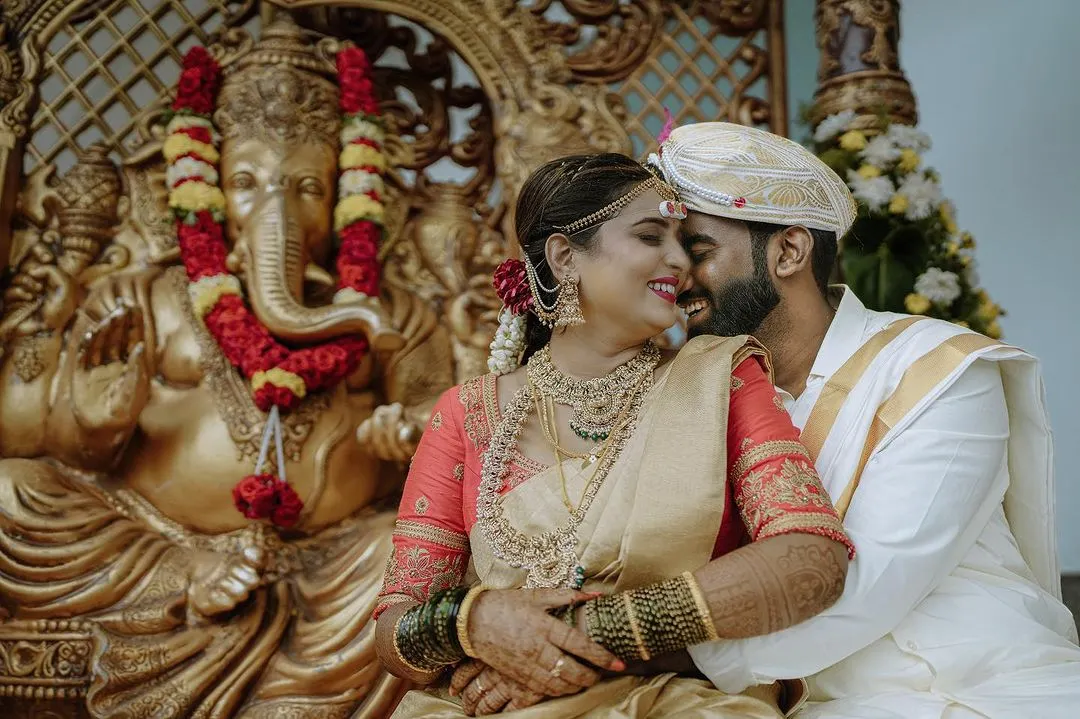 A quiet, happy moment between the bride and groom during their traditional South Indian wedding ceremony in Bangalore. I focus on capturing these genuine connections, blending candid photography with the richness of the cultural setting, like the ornate Ganesha sculpture in the background.