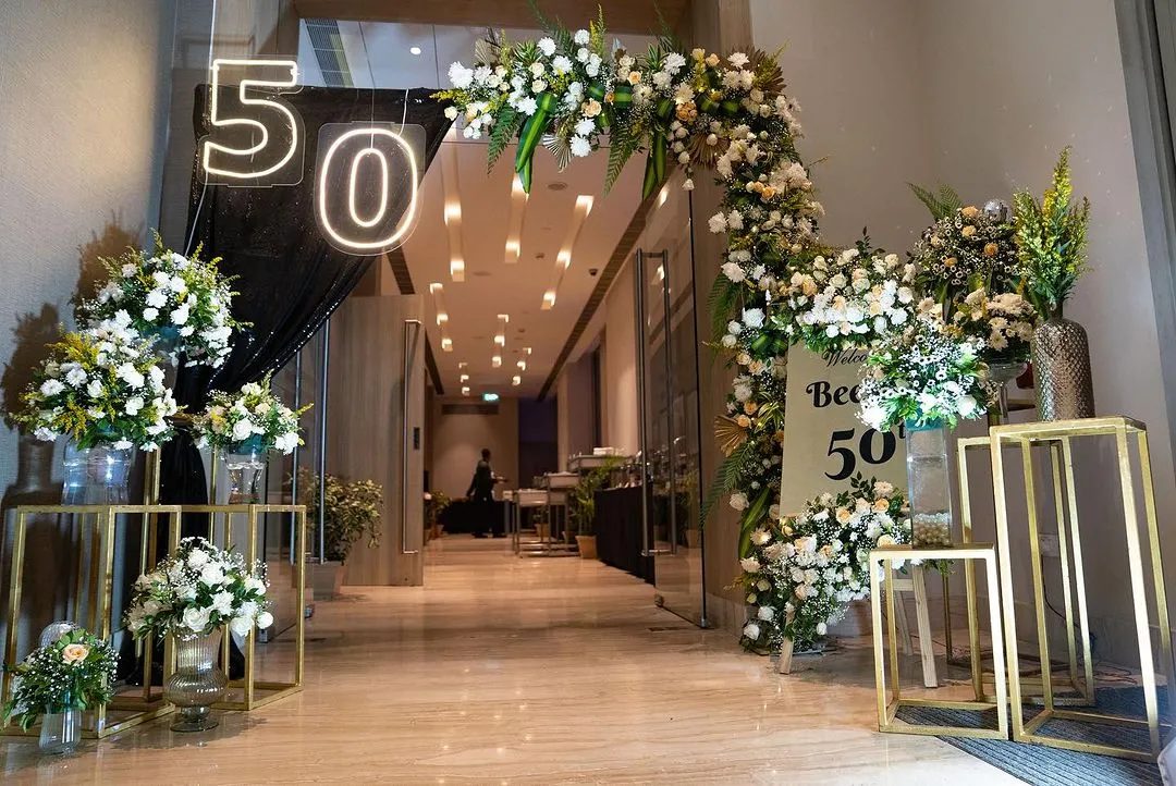 For a glamorous 50th birthday, I designed this grand entrance to set a tone of sophistication and excitement. The combination of lush white florals, dramatic black draping, and modern neon lighting created a truly fabulous welcome for the guest of honor and her friends.