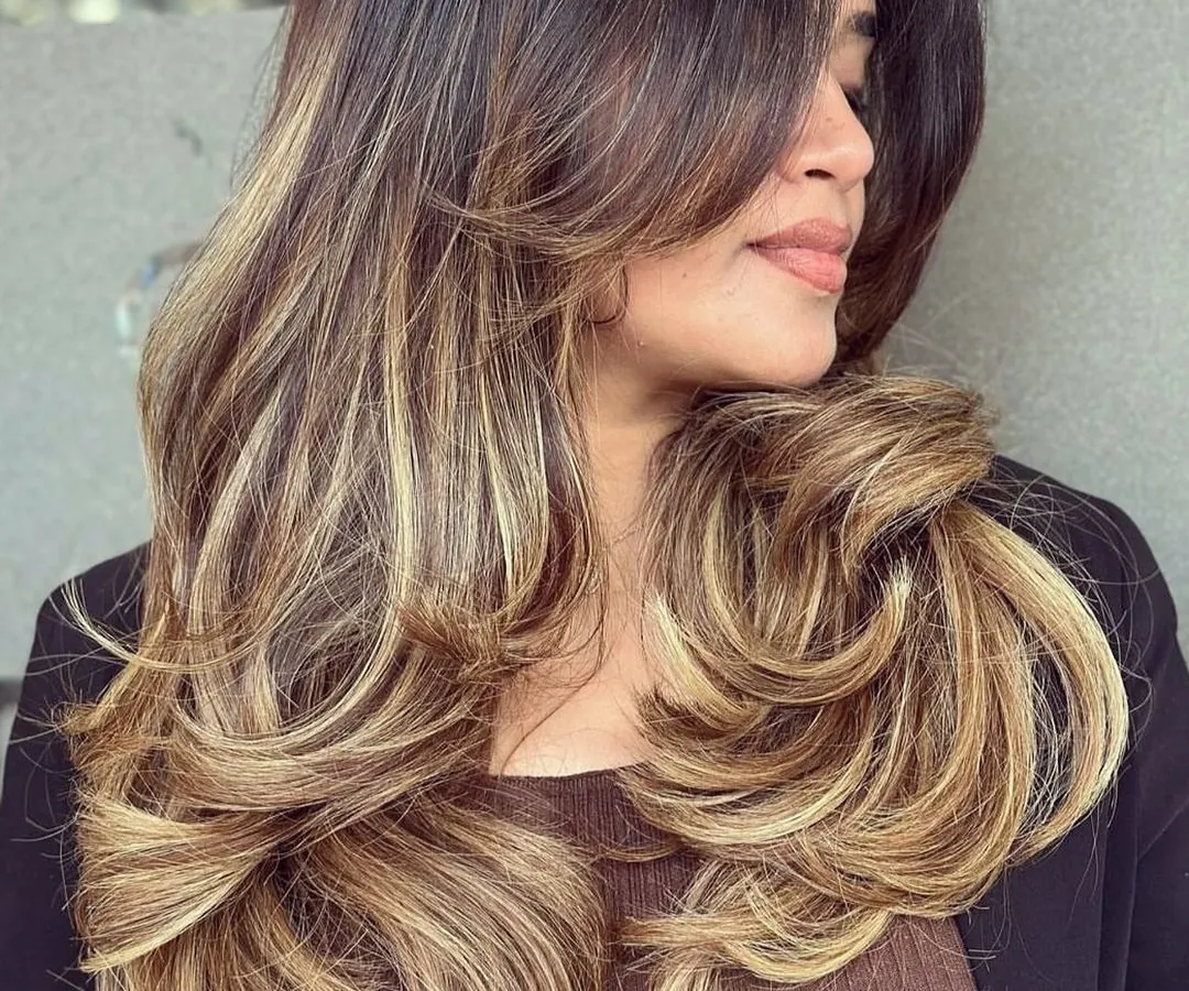 This is the popular butterfly haircut paired with a beautiful blonde balayage. The long, sweeping layers create movement and volume, while the expertly blended color gives a sun-kissed, natural-looking finish. This style is great for adding body to long hair.