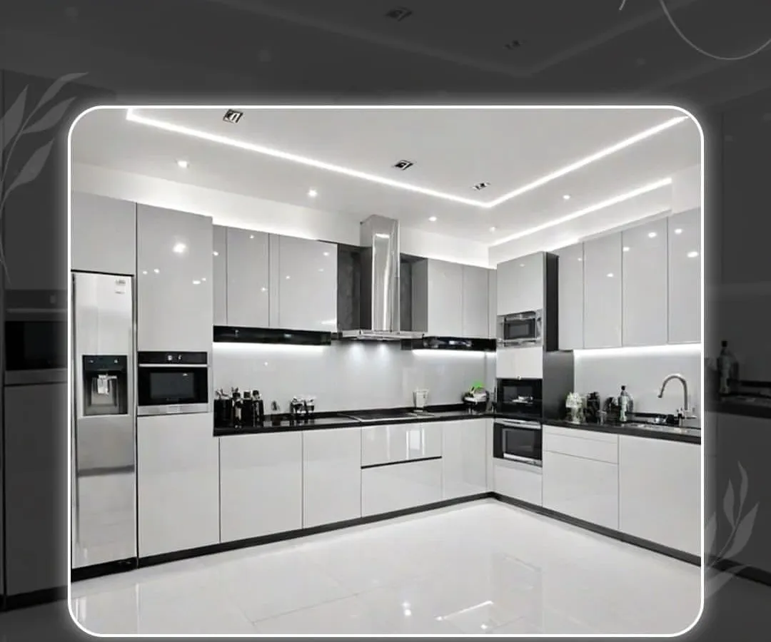A showcase of a modern, ultra-luxury modular kitchen in a striking high-gloss white and black theme. This L-shaped layout features integrated appliances, handleless cabinets, and layered lighting with spotlights and strip lights, creating a space that is both functional and visually stunning.