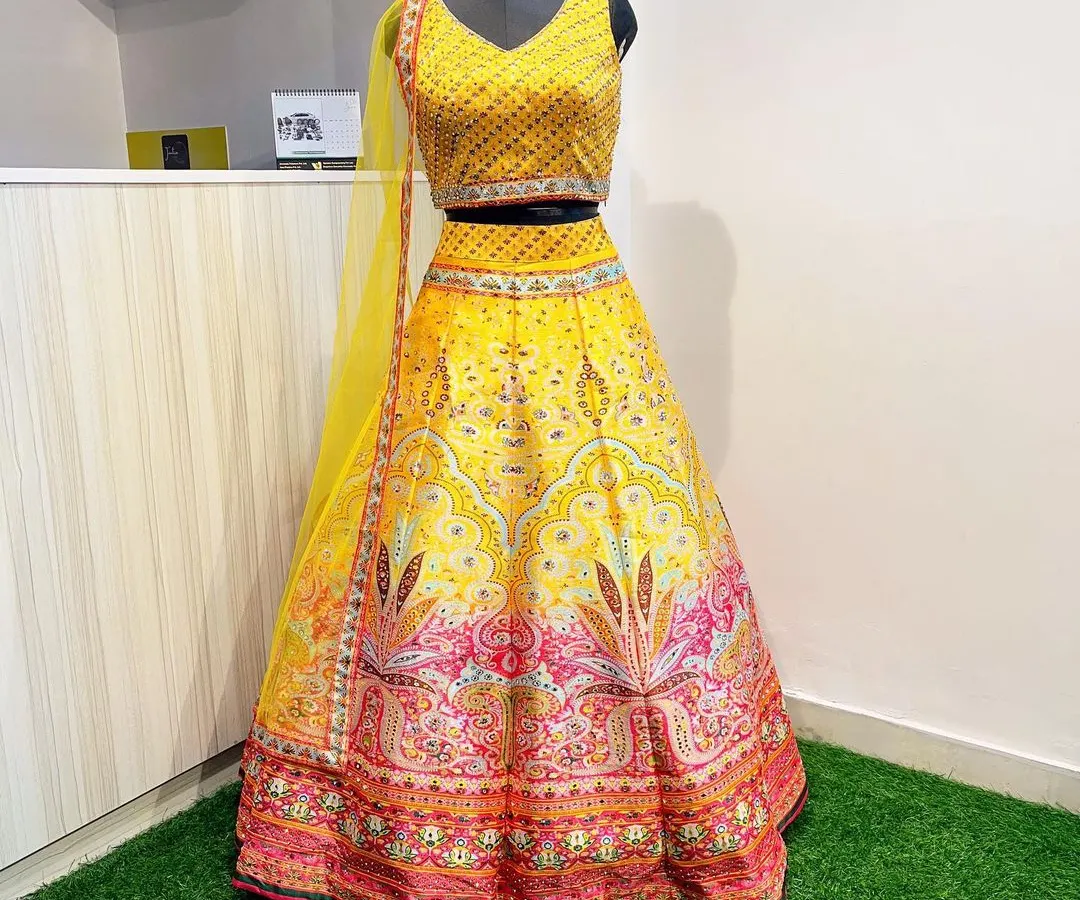 Looking for the perfect Haldi outfit? This vibrant yellow lehenga with colorful printed details and a sequined blouse is a fantastic choice for a fun and festive look.