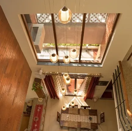 In the Reshma Residence, a large skylight transforms the central dining area into a dramatic, light-filled atrium. This top-down view shows how we engineer vertical spaces to create an open and airy atmosphere throughout the home, with pendant lights adding a warm glow.