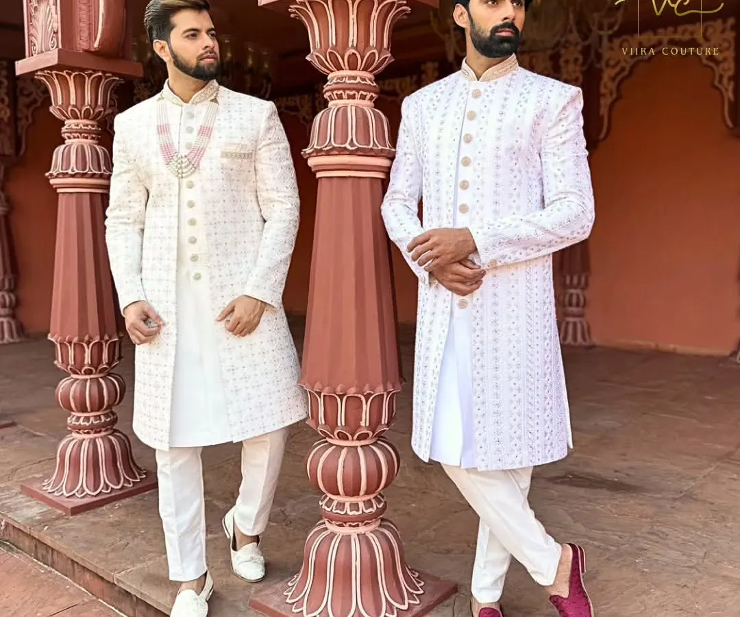 We create coordinated custom outfits for couples. Here, both grooms are in elegant white embroidered sherwanis, tailored for a perfect fit, ideal for a sophisticated wedding ceremony or a pre-wedding photoshoot.