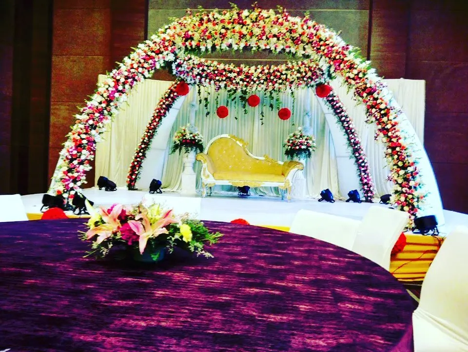 A closer view of a grand reception stage, highlighting the lush floral arch and elegant seating. The design ensures the couple is framed beautifully for photographs and ceremonies.