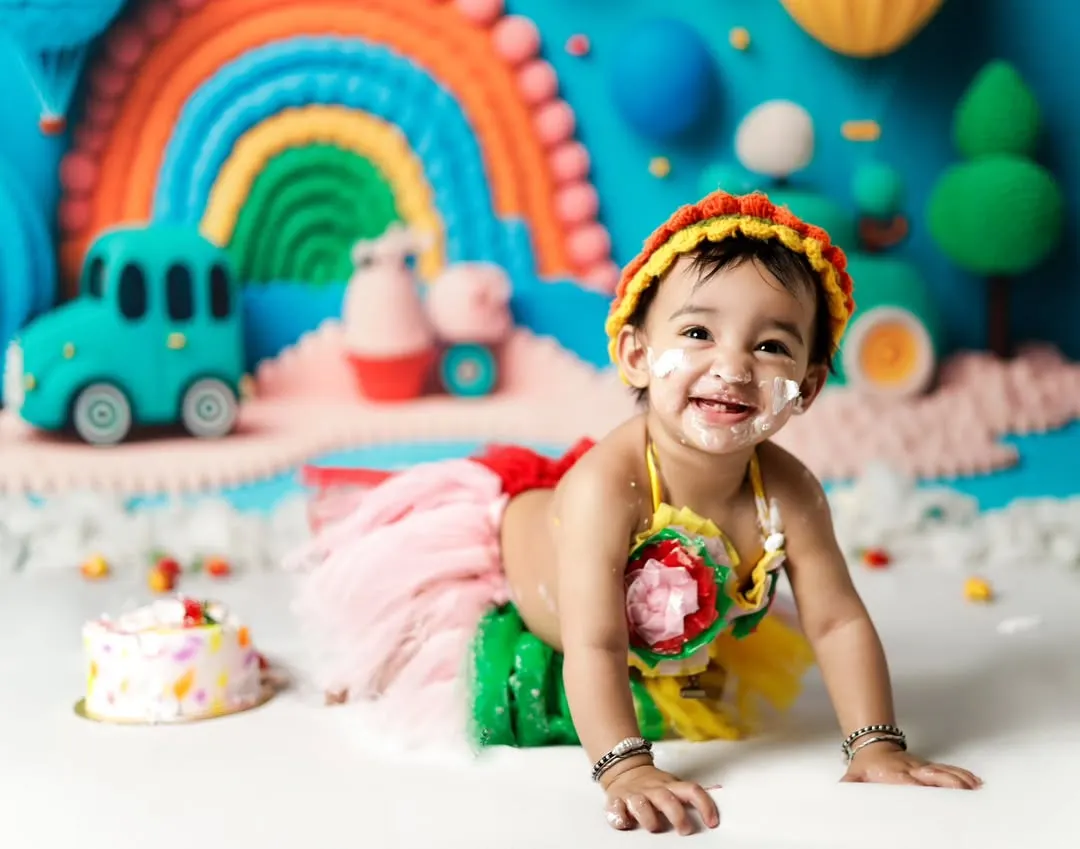 Look at that happy, messy face! Our cake smash sessions are all about pure joy and celebration. We create colorful, fun backdrops like this rainbow theme to make your baby's first birthday shoot unforgettable.