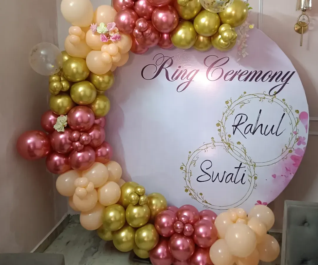 For your engagement or ring ceremony, I can create a personalized backdrop like this one. It features a custom-printed circular board with the couple's names, framed by a beautiful organic balloon arch in shades of rose, gold, and peach for a perfect photo opportunity.