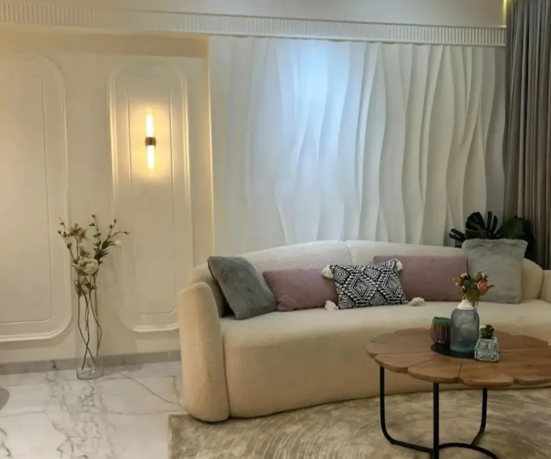 I believe in creating living rooms that are both serene and stylish. This space uses a soft, neutral palette, a plush curved sofa, and elegant 3D wall paneling to create a minimalist yet luxurious feel. The design focuses on texture and light to make the room feel warm and inviting.