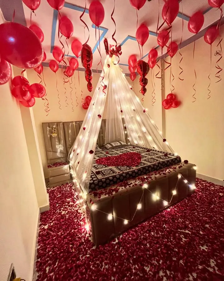 I create truly romantic and memorable experiences. This bedroom decoration features a beautiful canopy with fairy lights, hundreds of red balloons, and a floor covered in rose petals for the perfect surprise.