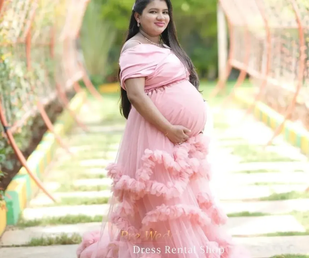 For a soft and romantic feel, this off-the-shoulder pink gown with layers of delicate ruffles is an ideal choice. It drapes beautifully to create a dreamy, ethereal look in any outdoor garden or park setting.