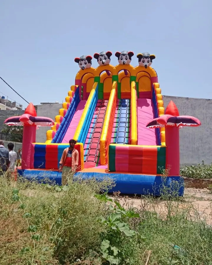 This is my giant Mickey Mouse themed inflatable slide, standing tall at 18x26 feet. The person standing next to it shows just how big and impressive it is, making it a guaranteed centerpiece for any large event or mela.