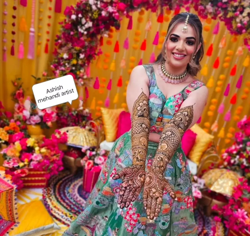 A radiant bride on her mehandi day. I love being part of these happy moments and creating designs that match the joy of the occasion, complete with a vibrant floral backdrop.