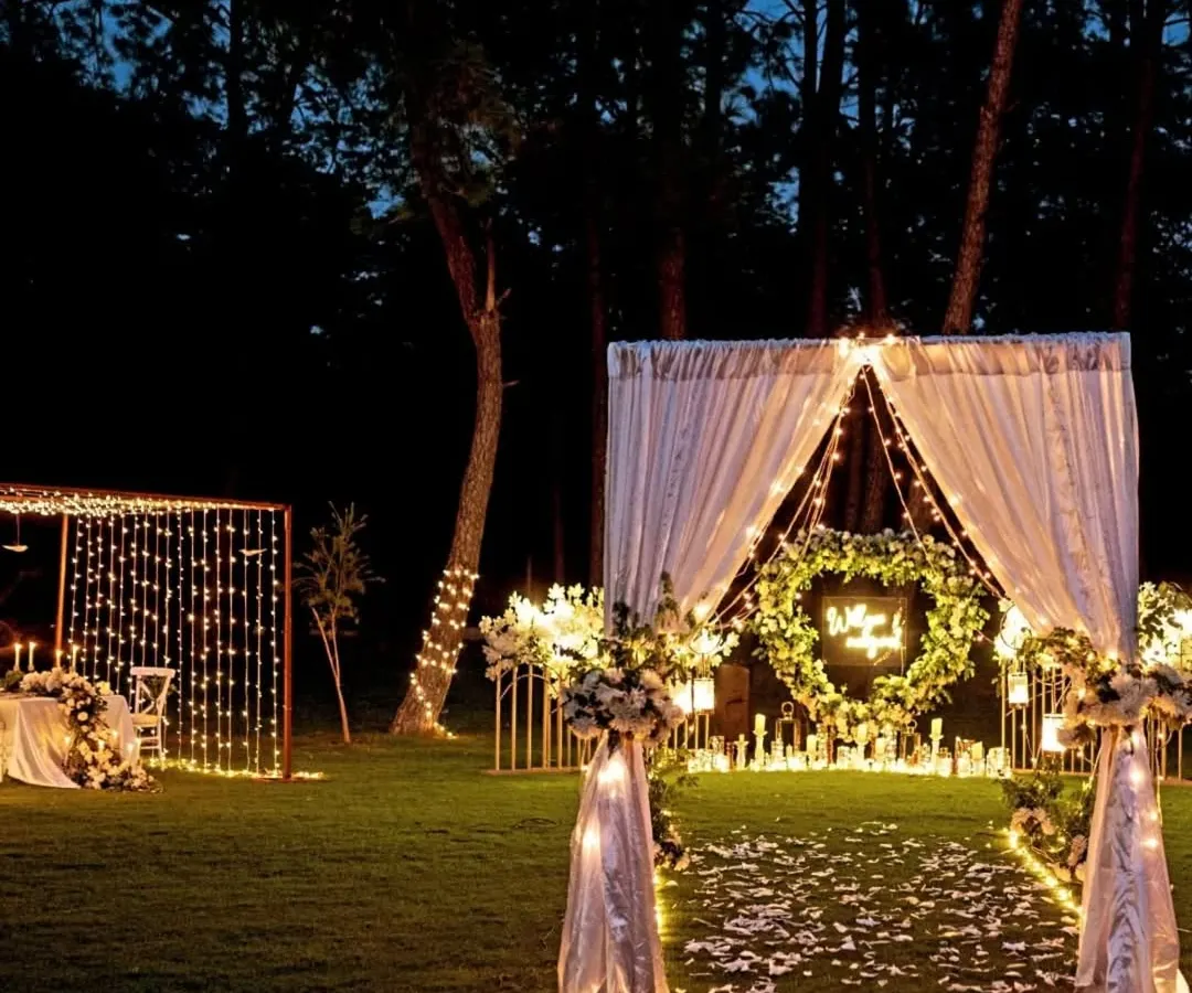 I love creating moments that feel like they're straight out of a fairytale. This outdoor proposal setup in Karjat combines the rustic charm of a forest with the elegance of fairy lights, a heart-shaped floral wreath, and a candlelit dinner for two. It’s a perfect example of how I blend natural beauty with personalized, romantic decor.