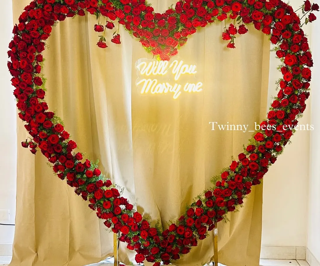 We love creating unforgettable proposal moments. This giant heart-shaped arch made entirely of fresh red roses, complete with a custom "Will You Marry Me" neon sign, makes for a definite yes.