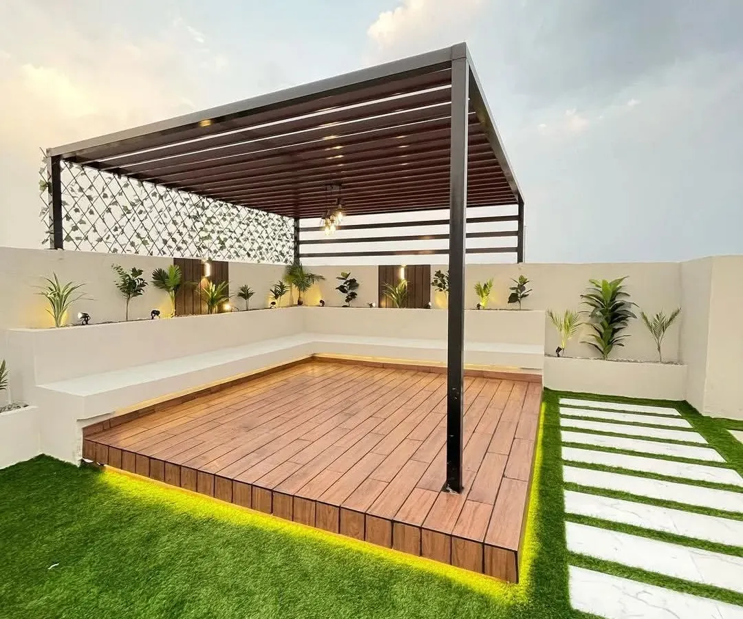 We built this expansive terrace retreat to be both beautiful and practical. The design features a sleek black pergola over a raised wooden deck, surrounded by durable artificial grass that stays green all year. The built-in bench seating provides ample space for guests, while the stone pathway adds a touch of elegance to the outdoor garden design.
