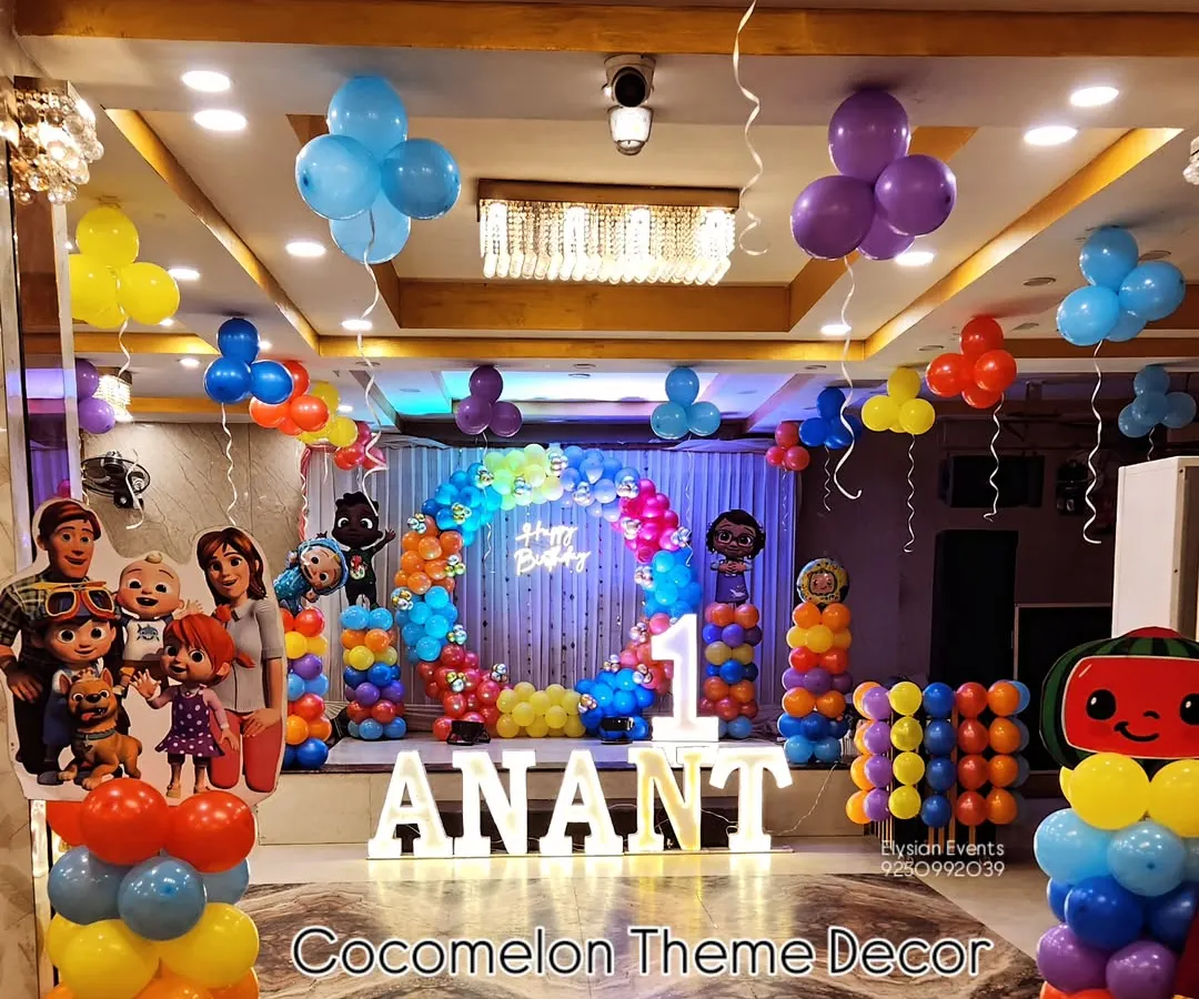 I bring popular themes to life, like this complete Cocomelon setup for a first birthday. The decoration includes large character cutouts, LED lettering for the name, a central balloon arch, and smaller balloon columns throughout the venue.