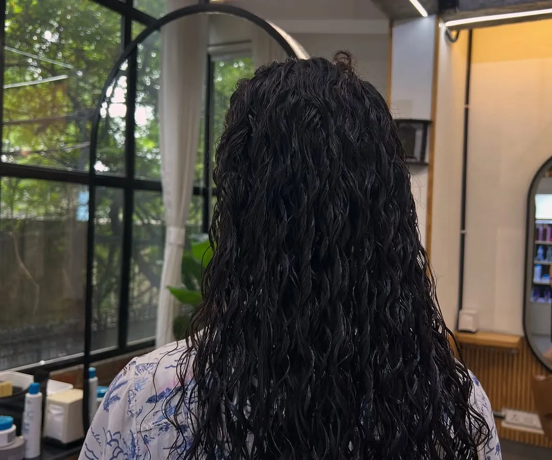 Here is the result of a hair perming service for long hair. The goal was to create uniform, defined, and bouncy curls that add significant volume and a completely new texture from root to tip.