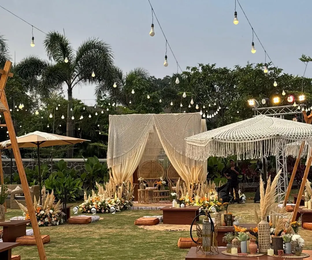 An enchanting bohemian sundowner setup, complete with low seating, macrame details, and pampas grass, all under a canopy of twinkling lights. This wide view captures the relaxed, yet utterly chic, vibe of the entire event.