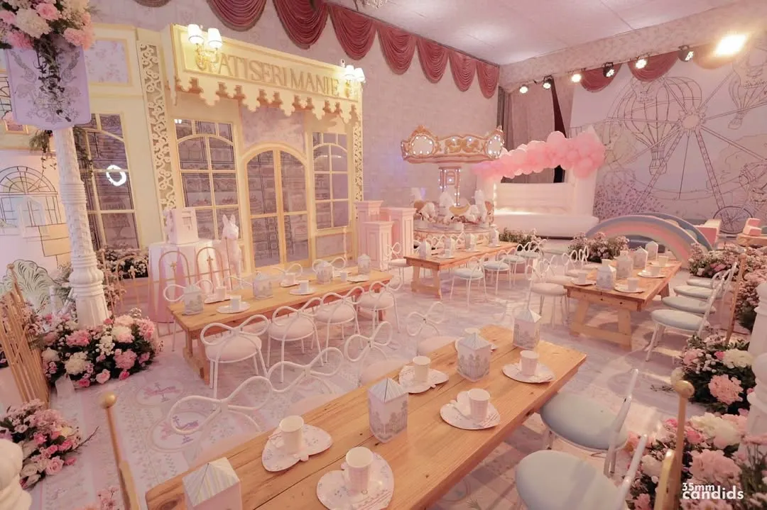 A whimsical Parisian patisserie theme brought to life for a child's birthday party. This immersive setup includes custom-built facades, soft pink florals, and elegant café-style seating for a truly magical experience.