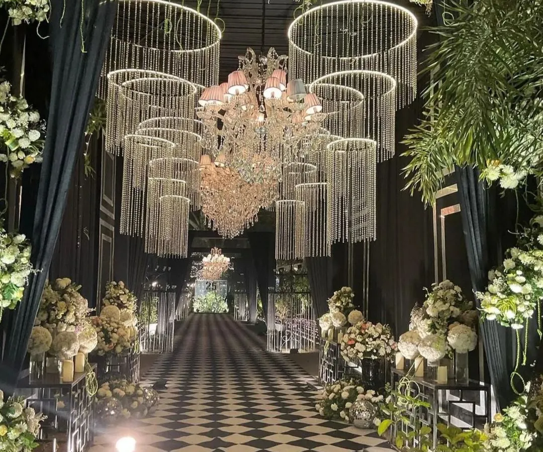 Your journey begins with a grand entrance. I love designing stunning passages like this modern black and white checkered aisle, framed by dramatic crystal chandeliers, to set a tone of sophisticated glamour from the very first step.