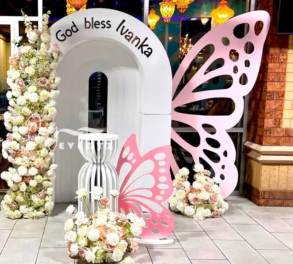 This butterfly-themed decoration for a First Holy Communion shows our modern and creative approach. The design uses custom-cut butterfly wings, elegant white arches, and beautiful floral towers for a whimsical and blessed celebration.