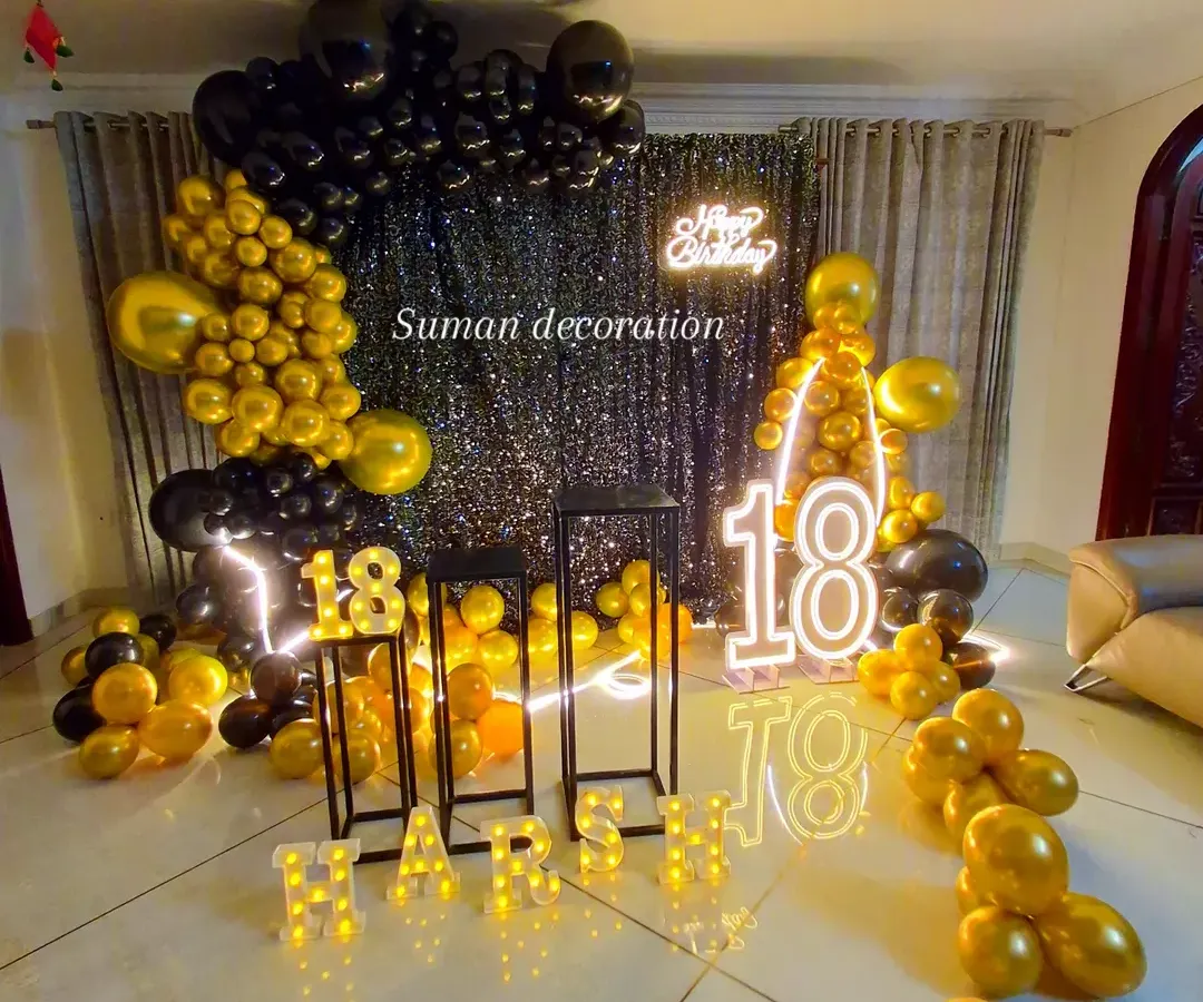 A stylish black and gold theme for an 18th birthday celebration. This setup features a black sequin wall, a "Happy Birthday" neon sign, large marquee numbers, and a dramatic balloon arch, perfect for creating a glamorous party atmosphere.