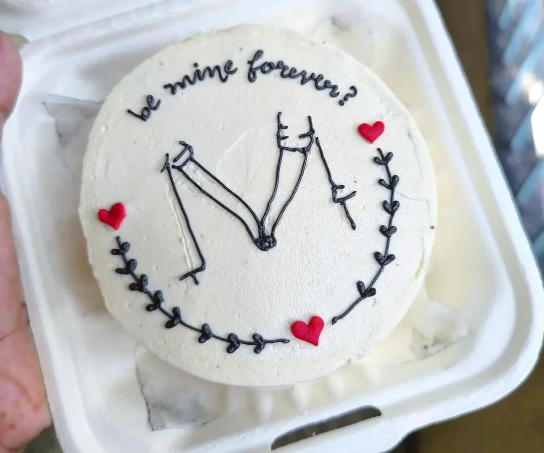 A simple question on a minimalist bento cake can make for the sweetest moment. This design features clean, hand-piped line art of a couple holding hands, perfect for anniversaries, proposals, or just because.