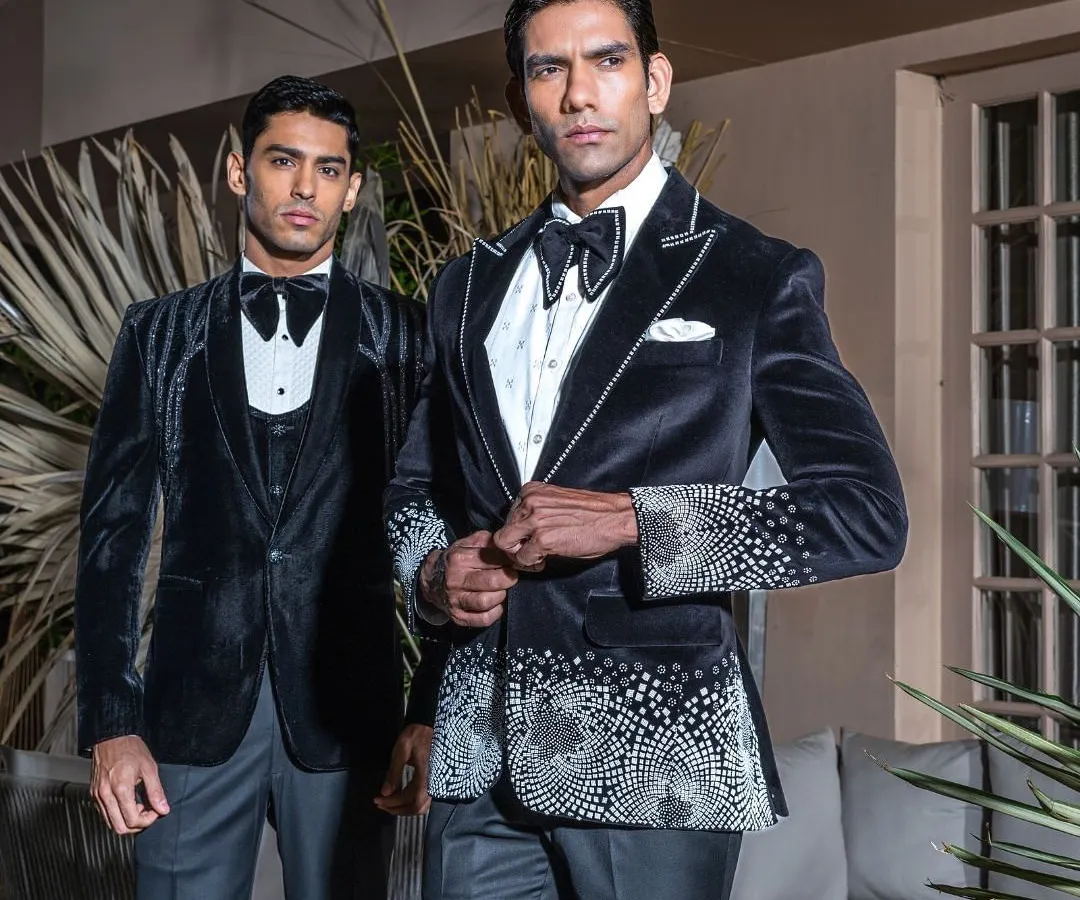 We craft wedding tuxedos that are designed to be as memorable as the occasion itself. This image showcases two of our signature velvet tuxedos, featuring intricate crystal work and a modern silhouette, perfect for the groom who seeks distinction and elegance.