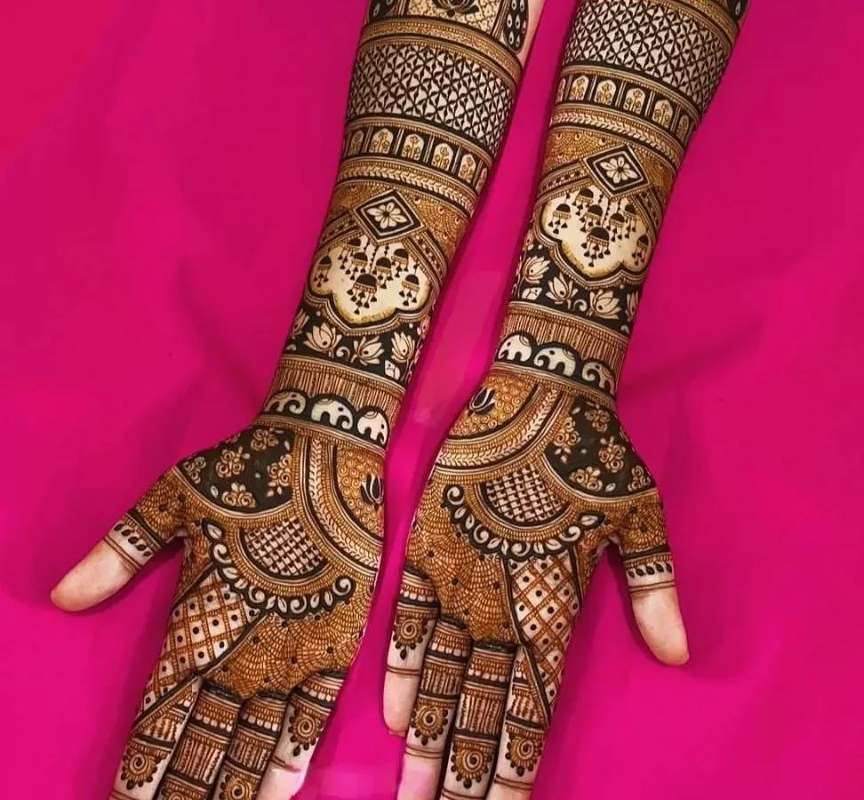 A perfect example of a full-coverage, symmetrical mehendi design. The fine lines, detailed jaal pattern, and lotus motifs create a stunning look that extends up to the elbows.