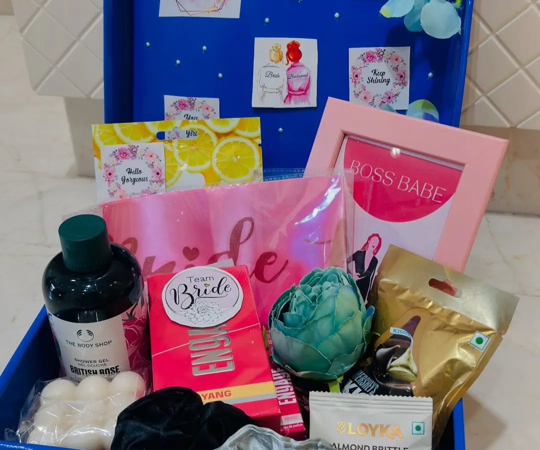 A peek inside our custom bridal hamper, packed in a reusable blue trunk. This one is filled with pamper essentials from The Body Shop, a "Boss Babe" frame, a "Team Bride" sash, and sweet treats to celebrate the bride-to-be.
