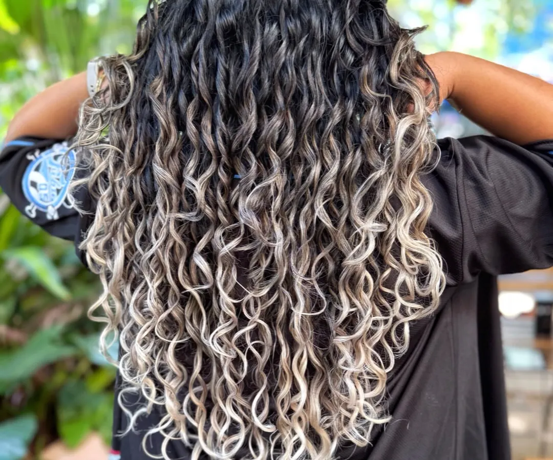We are obsessed with transforming curls. Here, we achieved a stunning silver ombre on long, curly hair while maintaining the integrity and definition of each curl. This look was created with a careful bleach and tone process, followed by our signature CGM-friendly styling.