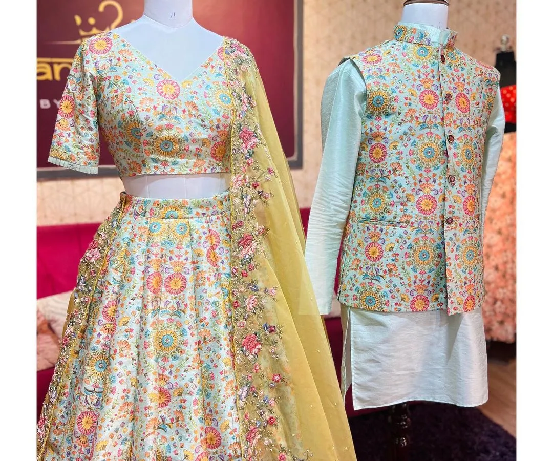 This coordinated couple set is perfect for sangeet or engagement ceremonies. It includes an off-white lehenga with vibrant multi-color floral embroidery, paired with a mint-green kurta and a matching embroidered Nehru jacket.