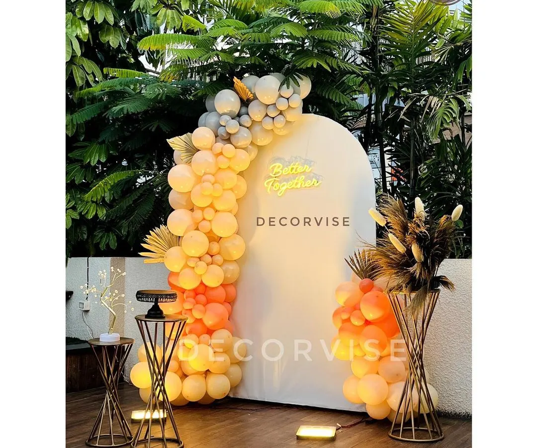 I created this chic outdoor setup for an engagement party. The 'Better Together' neon sign on a modern white arch, paired with a sunset-hued balloon garland, makes for a perfect photo opportunity for the couple.